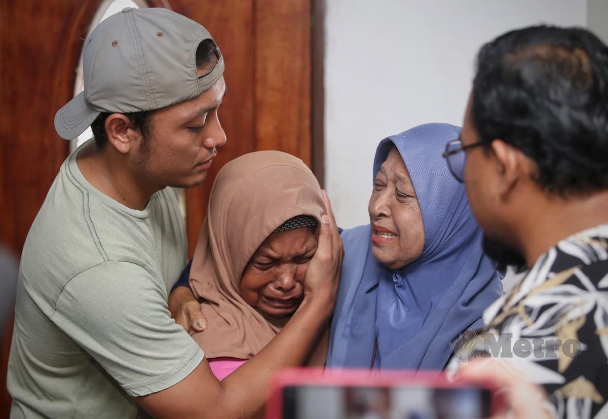 SYAZWAN menenangkan ibunya Khalidah Ahmad, 64, (dua dari kiri) bersedih dengan Shahril yang dipercayai dipukul serta diikat selepas kemalangan dekat Taman Pelangi Semenyih 2, Kajang, Selangor. FOTO Azrul Edham.