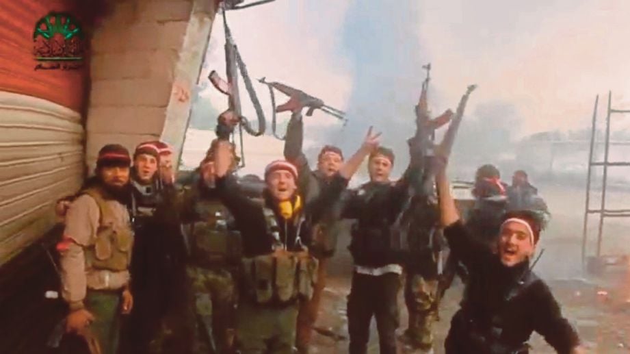 GAMBAR yang dipetik dari rakaman video menunjukkan pejuang penentang menjulang senjata mereka dan bersorak, didakwa dirakam di Damsyik, ibu negara Syria. - Reuters 