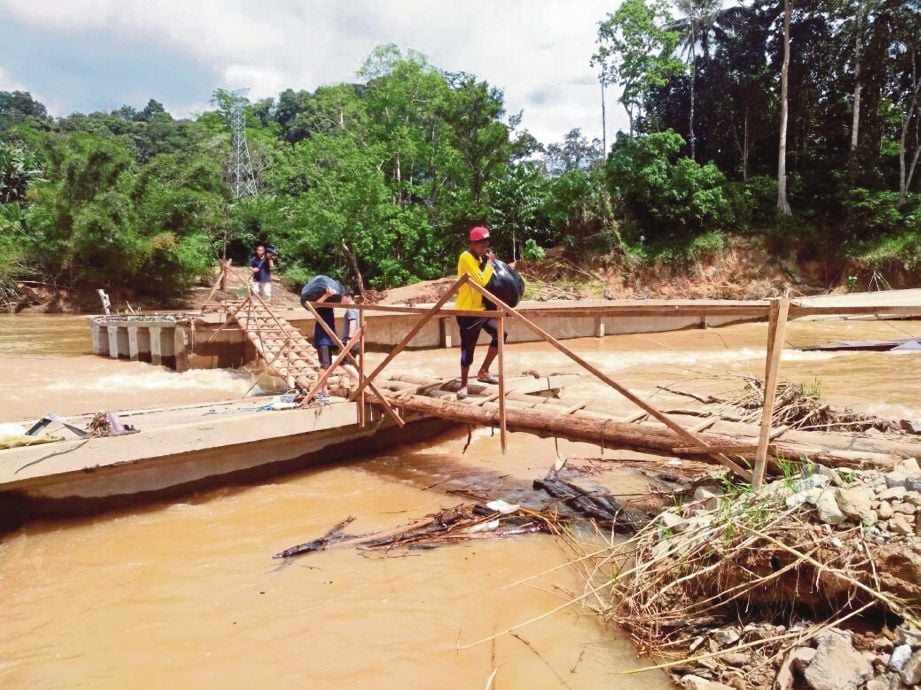  PENDUDUK menyeberangi Sungai Nenggiri menggunakan empat titi menghubungkan jambatan runtuh di Kampung Pulau Setelu, Gua Musang.