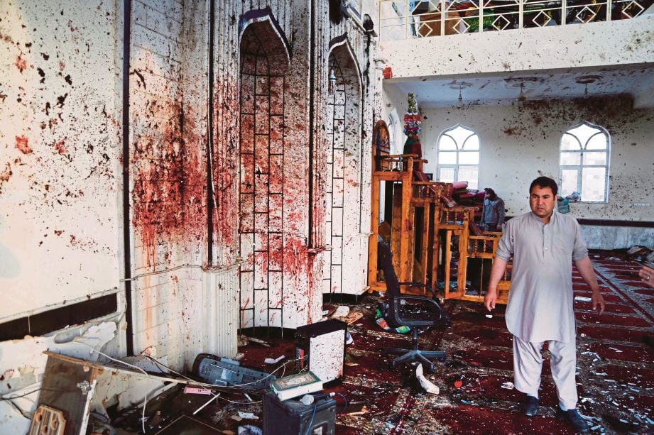 SEORANG lelaki berjalan berhampiran dinding masjid yang dipenuhi dengan kesan darah. - EPA