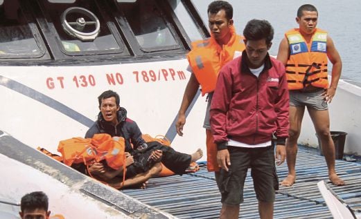 SEORANG penumpang yang berjaya diselamatkan memaut mayat anaknya selepas tiba di pelabuhan di Kolaka, tenggara Sulawesi, kelmarin. 