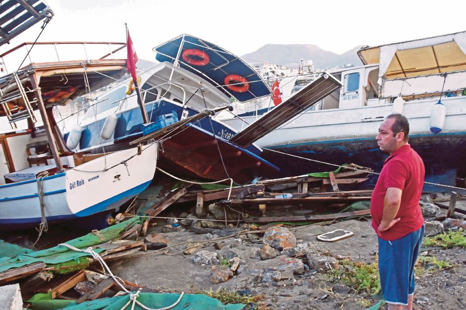 SEORANG lelaki melihat bot yang rosak di Bodrum, Turki,  berikutan gempa bumi semalam.  - AFP 