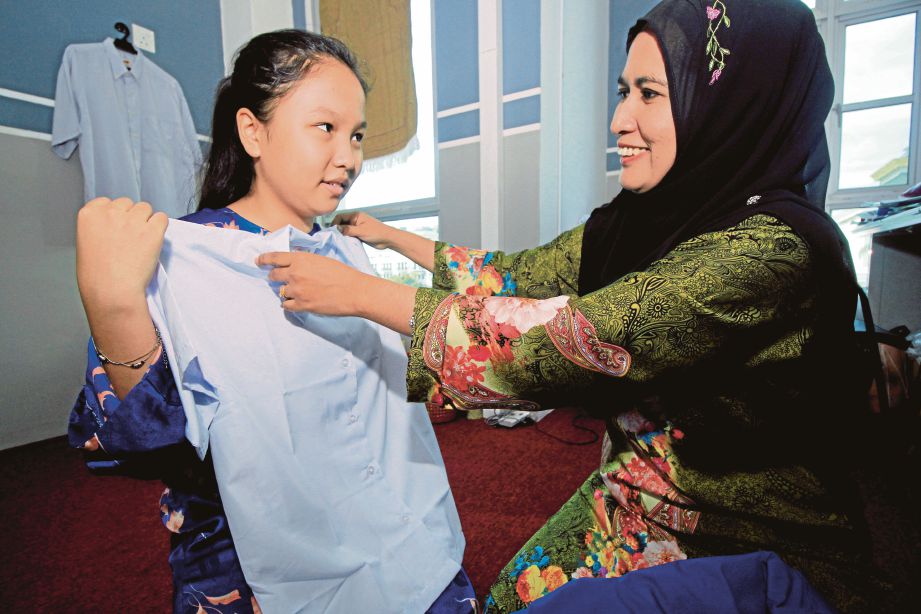  Zalelawati     membantu  Michelle  mencuba baju sekolah yang diterima daripada bantuan persekolahan.  
