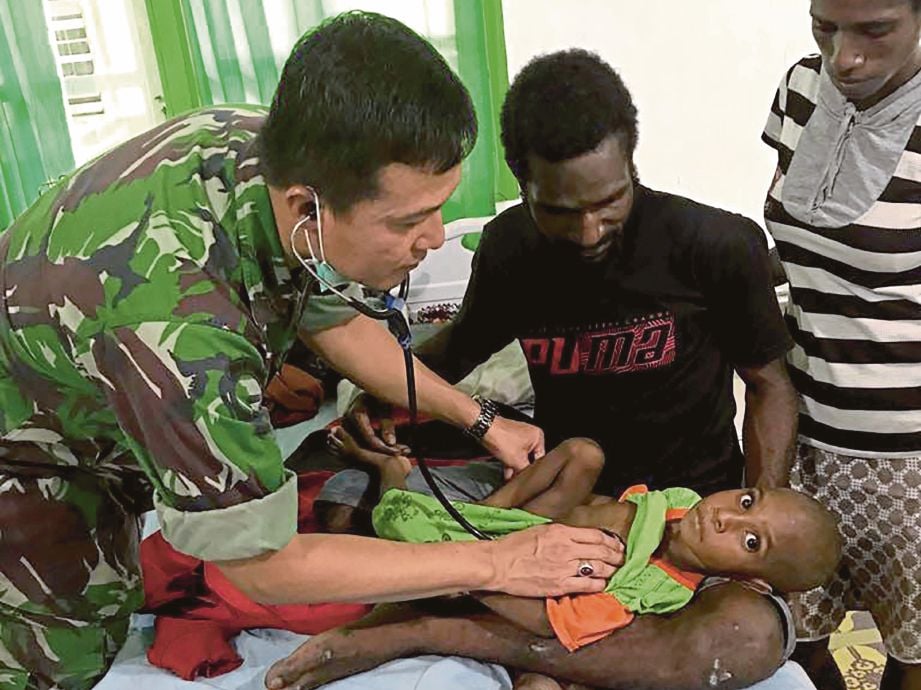 SEORANG doktor tentera merawat  kanak-kanak yang sakit di sebuah pusat perubatan di Asmat di wilayah Papua, Indonesia. - AFP