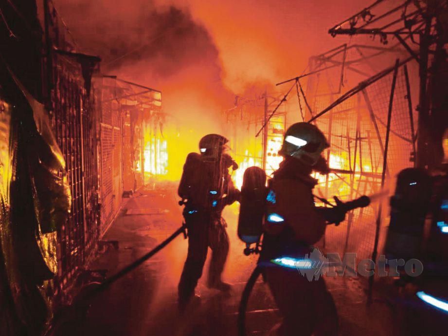 ANGGOTA bomba memadamkan kebakaran yang berlaku di Bazar Melayu Masjid India, awal pagi semalam.