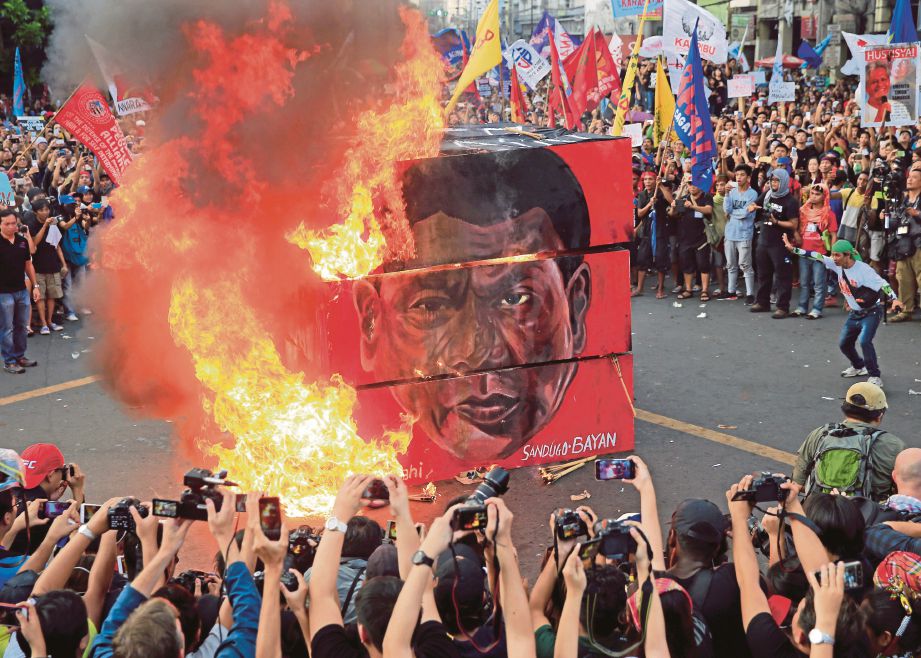 PENUNJUK perasaan membakar kain rentang dengan wajah Duterte ketika bantahan di luar istana presiden di Manila. - Reuters 