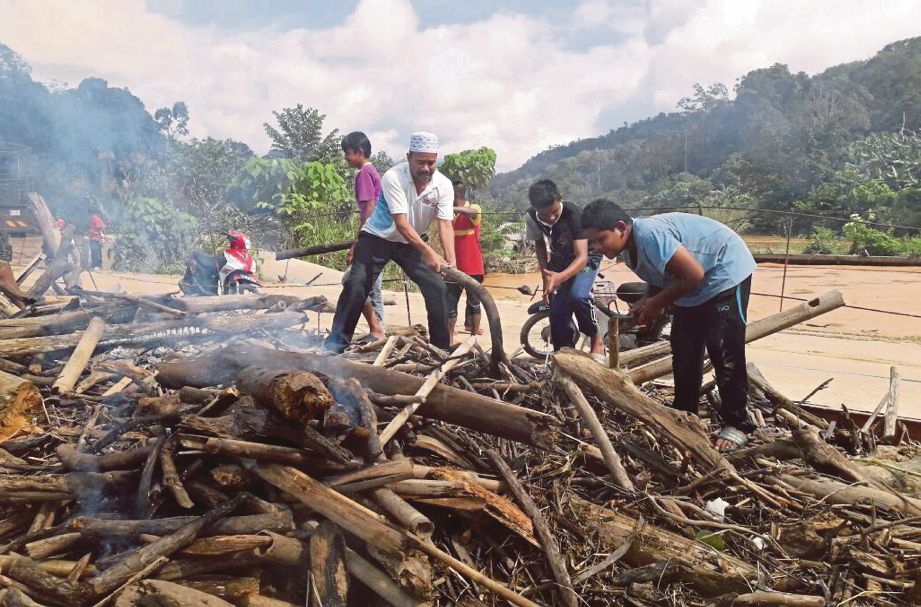  Penduduk kampung membuang longgokan sampah di  jambatan Kampung Pulau Setelu akibat limpahan air sungai.