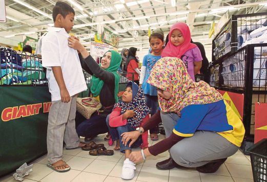  Sukarelawan Harian Metro membantu  murid miskin dan anak yatim  memilih pakaian dan kasut di Pasaraya Besar Giant Kijal.