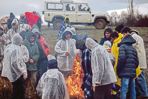 SEKUMPULAN pelarian Afghanistan memanaskan badan di keliling unggun api ketika menunggu dibenarkan melintas sempadan dari Macedonia ke Serbia.