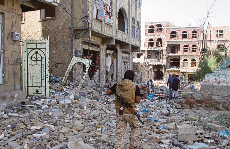 SEORANG pejuang prokerajaan melintasi bangunan yang rosak teruk akibat pertempuran pada hari kedua gencatan senjata di Taiz, barat daya Yaman, semalam.  - Reuters