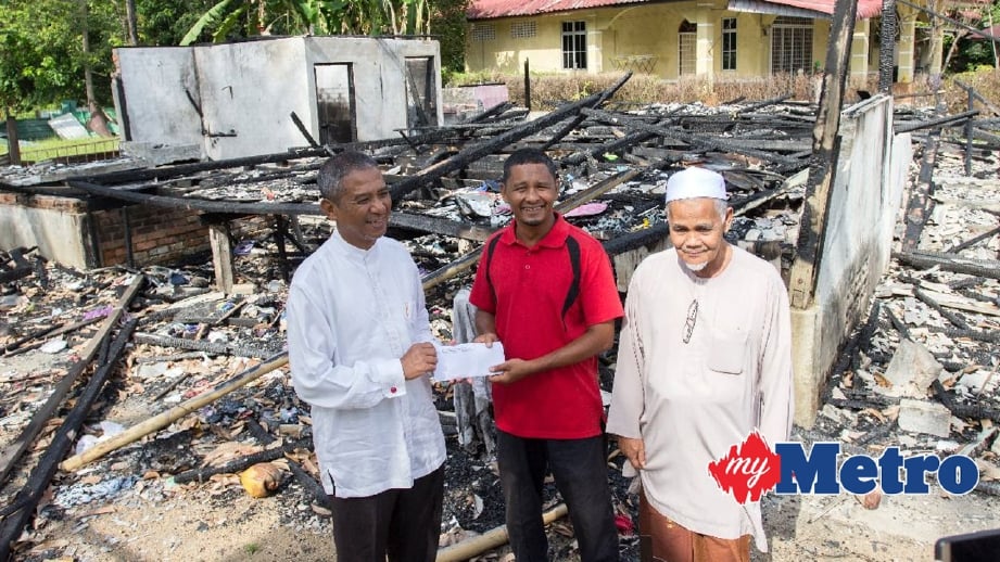 DR NIK AZLAN (kiri) menyampaikan sumbangan kepada Zaki Ishak. FOTO Nik Abdullah Nik Omar