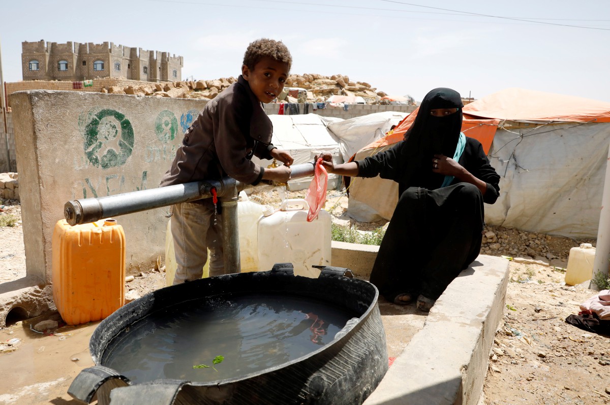 WANITA Yaman dan anak lelakinya mengambil air bersih dari tangki disediakan di kem pelarian. FOTO EPA 
