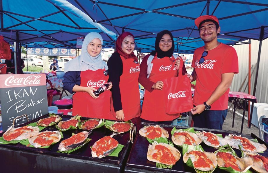    EKSEKUTIF Acara Coca-Cola Azhar Shikh Hatim (kanan) menyampaikan cenderahati kepada  Fazlila  (tiga dari kiri) di Bazar Ramadan  Gelang Patah.