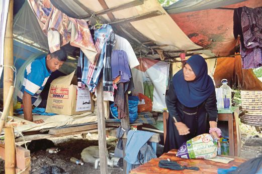 MUHAMMAD Saiful   membantu ibunya mengemas barang keperluan untuk dibawa ke rumah sementara.