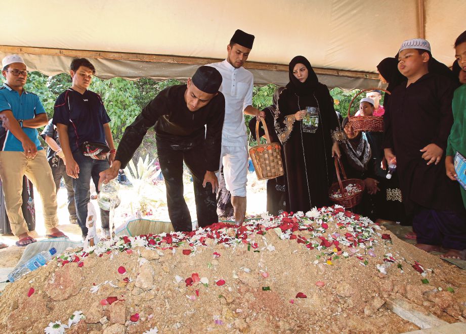 Mohd Zaquan Adha dan   Mohd Aidil Zafuan  menyiram air mawar di pusara ayah mereka   di Tanah Perkuburan Islam Makam Haji  Said. 