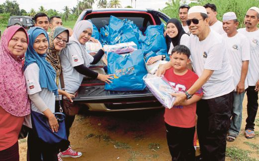 NORAZILA (empat dari kiri) mengagihkan kit praRamadan kepada sukarelawan di Kampung Wakaf Merah, Tendong.  