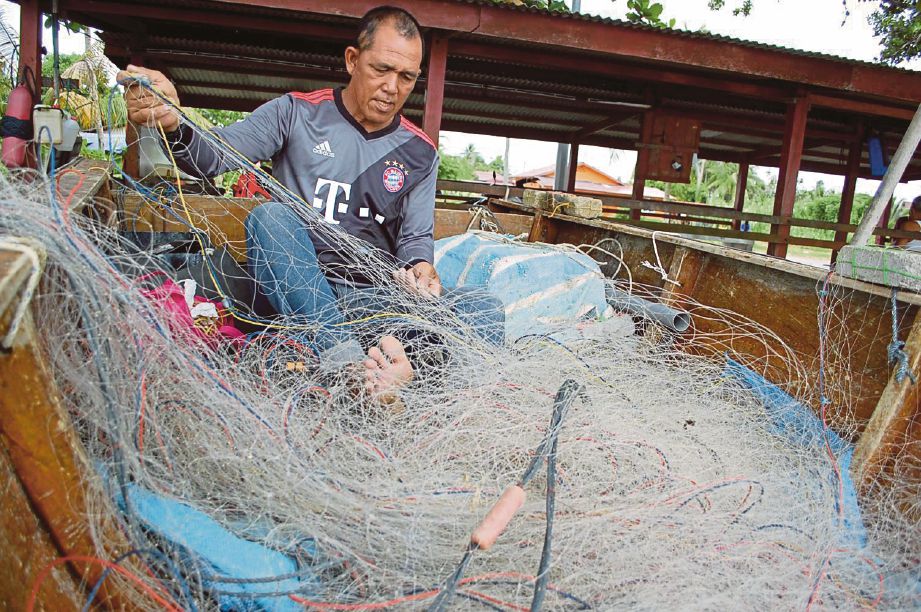 Nelayan, Borhan Yusof menyirat jaring dalam perahunya.