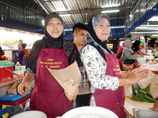 CHOM (kiri) dibantu anaknya, Suwati menjual nasi kerabu ‘power’ di pasar Pertubuhan Peladang Kawasan di Kuala Kubu Bharu.