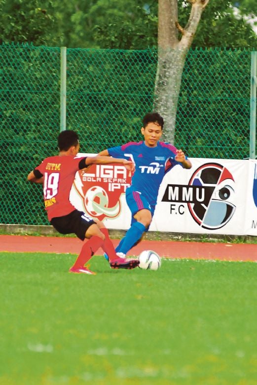 PEMAIN MMU, Ahmad Faiz (kanan) cuba melepasi kawalan pemain UiTM Perlis dalam saingan di Stadium Cyberjaya. Tuan rumah tewas 0-1.