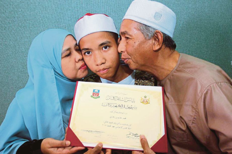 MUHAMMAD Hazim  (tengah) dicium  ibu bapanya, Zahari Isa dan Sarimah Hassan selepas diumumkan Tokoh Tahfiz 2017.