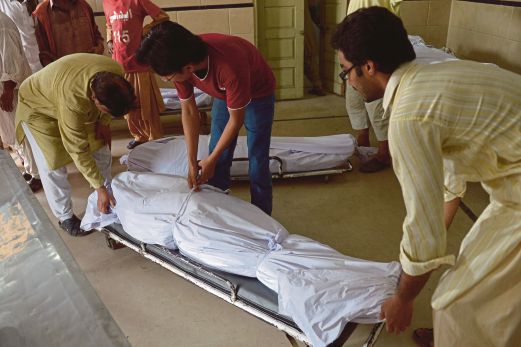 SUKARELAWAN menyiapkan jenazah mereka yang mati akibat cuaca panas ke bilik sejuk beku rumah mayat Edhi di Karachi.
