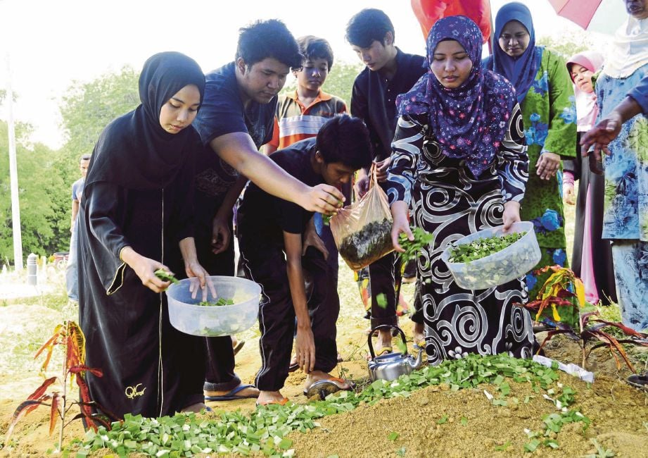 HERA (kiri) dan Faizal Hakim  menyiram air mawar di pusara ibu mereka  di Tanah Perkuburan Islam Kampung Lubuk Merbau,Padang Rengas.