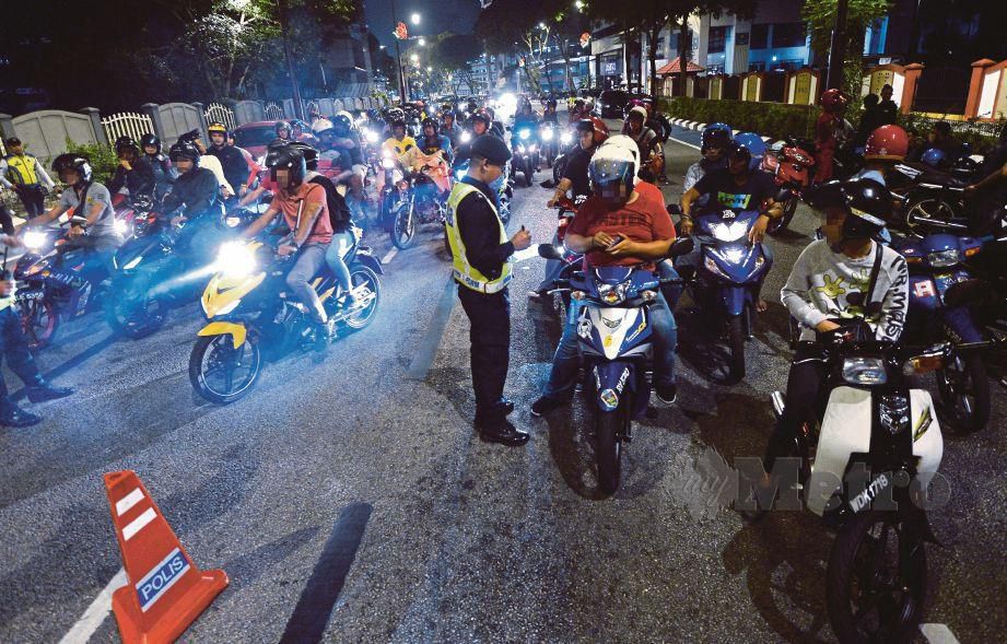 POLIS memeriksa penunggang motosikal dalam  sekatan jalan raya.