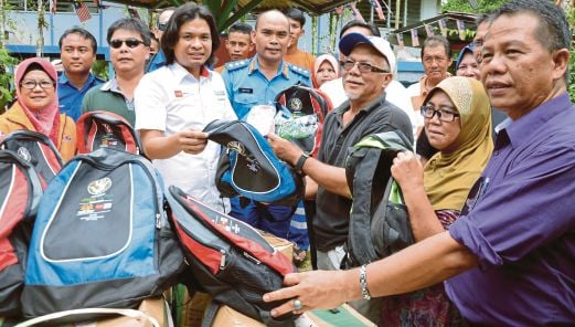   Shamran (tengah) mengagihkan sumbangan daripada Tabung Bencana NSTP dan Media Prima kepada  mangsa   banjir dari Kampung Endap.  