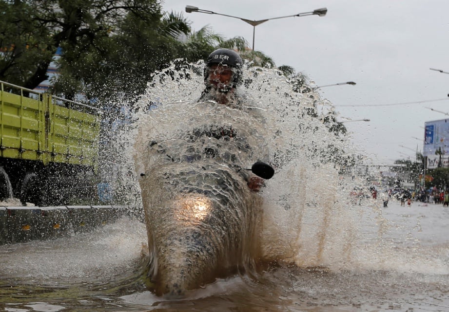 SEORANG penunggang motosikal meredah jalan raya yang dilanda banjir di  Mangga Dua di Jakarta, kelmarin. - Reuters