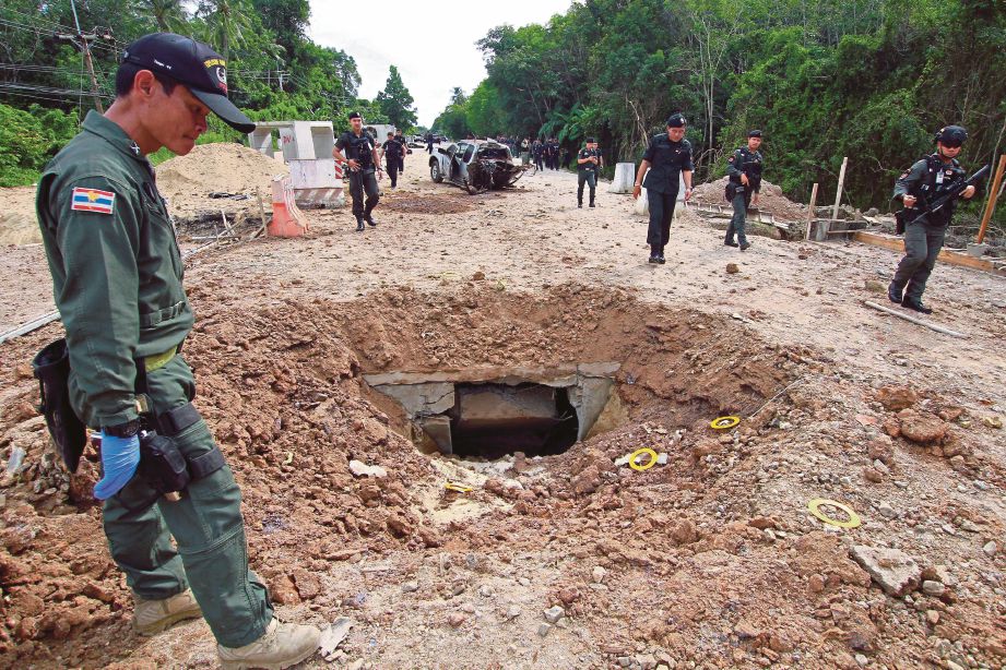 KAWAH yang terbentuk di jalan raya selepas serangan bom di daerah Sai Buri, Pattani, Thailand yang mengorbankan empat askar semalam. - Reuters