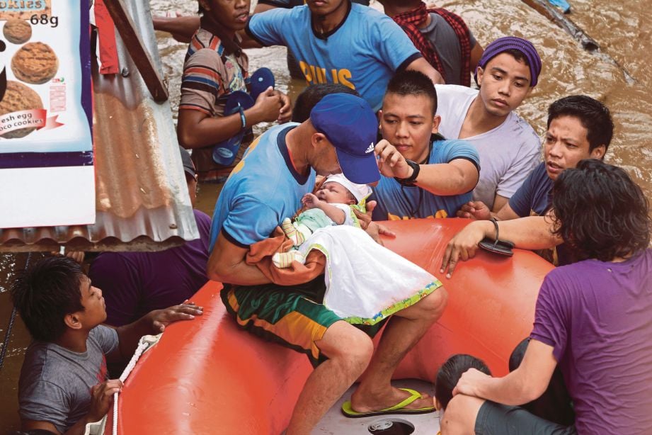ANGGOTA penyelamat memindahkan seorang bayi dari sebuah kediaman yang dilanda banjir di Cagayan City di selatan Filipina semalam. - AFP