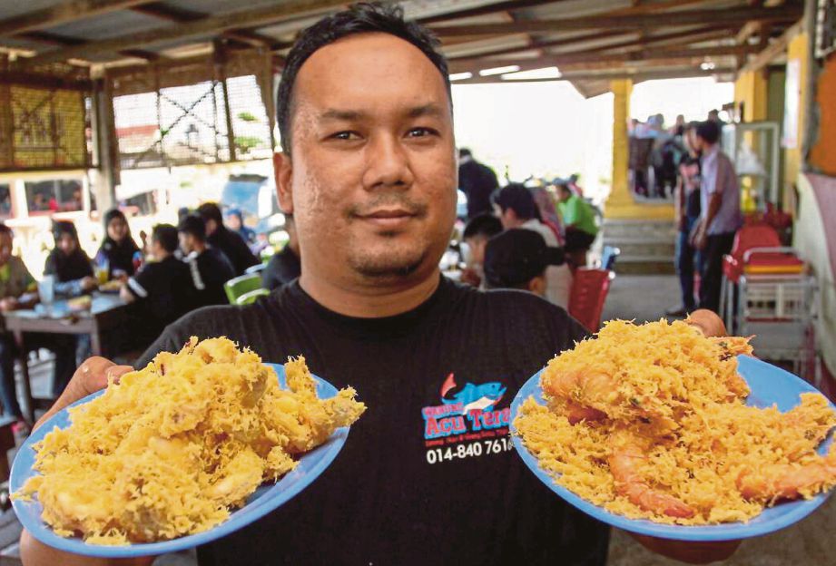  Mohammad Firdaus  menunjukkan pelbagai makanan laut   goreng tepung  yang dijual di kedainya di   Pantai Sabak.  