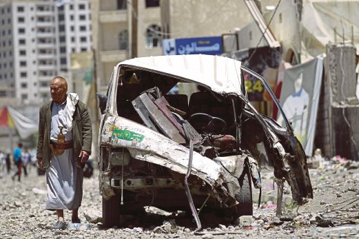 SEORANG lelaki Yaman berjalan berhampiran sebuah kenderaan yang rosak teruk selepas serangan udara Saudi berhampiran pangkalan tentera Fajj Attan, Sanaa, semalam.  