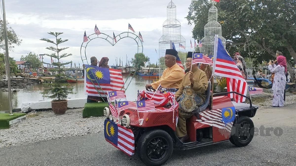 MOHAMAD Subhi (kanan) menaiki buggy dihias dengan Jalur Gemilang dan dibawa bersiar-siar di sekitar kawasan Kampung Kuala Dulang Kechil. FOTO Zuliaty Zulkiffli