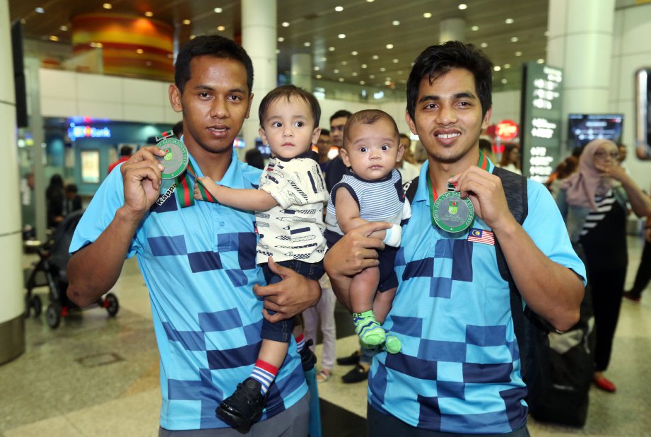 PEMAIN hoki negara, Faizal Saari (kiri) bersama Fitri serta anak mereka Faleeq Jafran Faizal, 1 tahun dan Muhammad Yusuff Zahran Mohd Fitri, 5 bulan ketika tiba di KLIA. FOTO/MOHD FADLI HAMZAH 