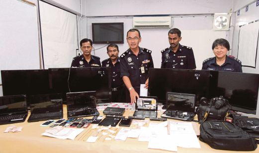 MOHD Azmi (tengah) menunjukkan barang curi yang dirampas.