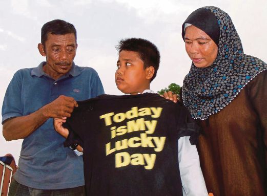 SANIJO  bersama Markina  dan  Mohd Romli menunjukkan baju yang dipakainya  ketika kejadian dihanyutkan arus deras.