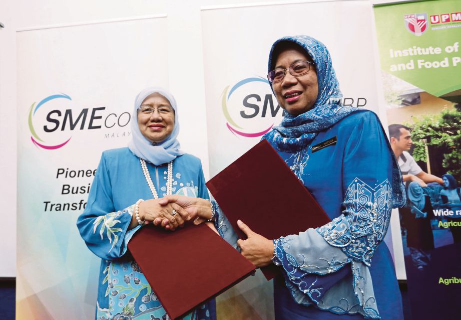 DR Aini  (kiri) bertukar dokumen  dengan  Hafsah pada  majlis menandatangani MoU antara SME Corp dan UPM, semalam.