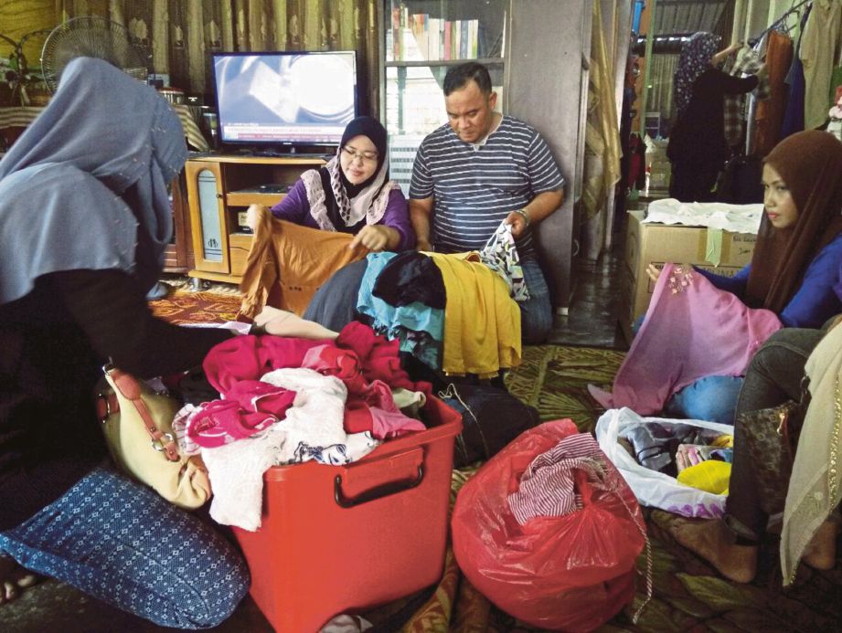  Arbani  bersama  Siti Rohani melayan pelanggan yang memilih pakaian di rumah mereka.