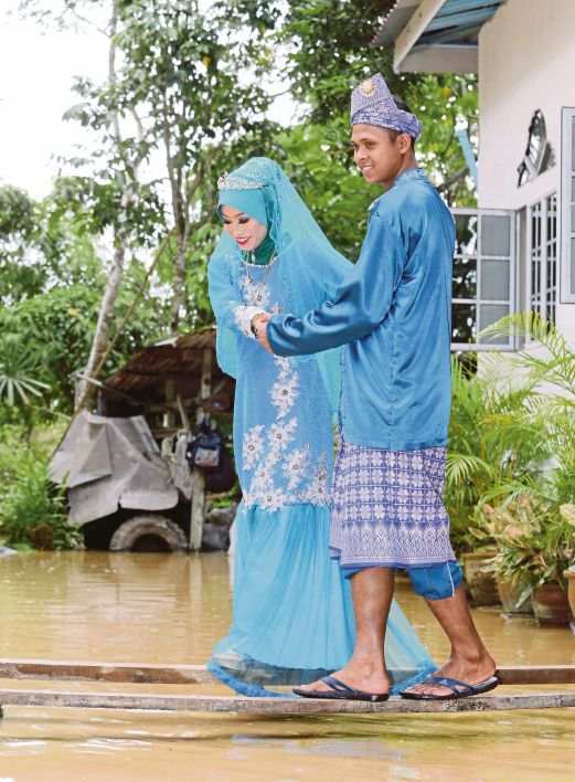 MOHD Saiful bersama pasangannya, Nur Faizah meniti di atas kayu selepas rumah mereka dilanda banjir kilat.