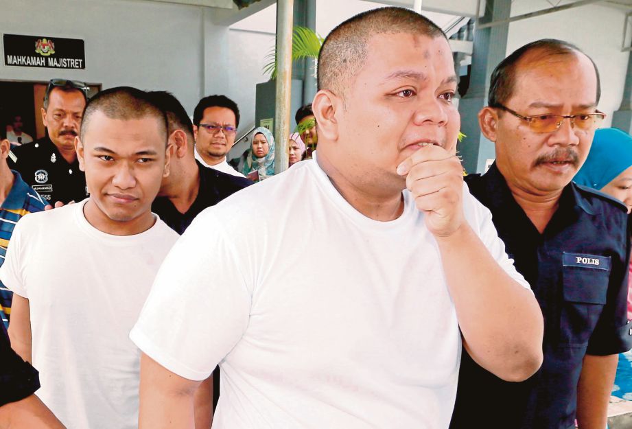 MUSTAZA (depan) dan Mohd Azim Luqman (belakang) diiringi anggota polis ketika keluar dari Mahkamah Majistret.