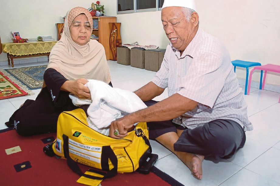 MOHD Tamin (kanan) bersama isterinya, Latifah Md Yusof mengemas kain ihram.