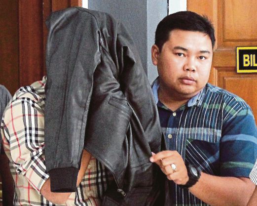 YUSRI (kiri) menutup muka dengan jaket selepas keluar dari kamar mahkamah.