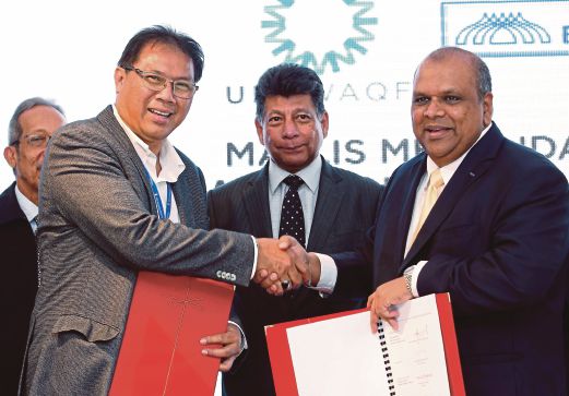 Pengerusi Bank Muamalat (tengah) Tan Sri Dr Mohd Munir Abdul Majid menyaksikan pertukaran perjanjian di antara Ahmad  (kiri) dan Ketua Pegawai Eksekutif Bank Muamalat, Datuk Mohd Redza Shah Abdul Wahid.