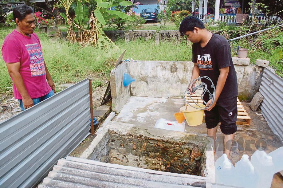 PENDUDUK mengambil air dari perigi di Kampung Bukit Darat, Tanjung Kling. 