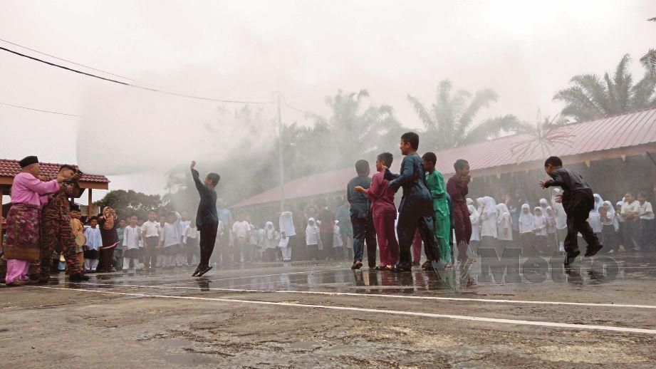 ANGGOTA bomba menyiram murid ketika program  berkhatan di Sekolah Kebangsaan Parit Kassan, Tangkak. FOTO Ahmad Ismail