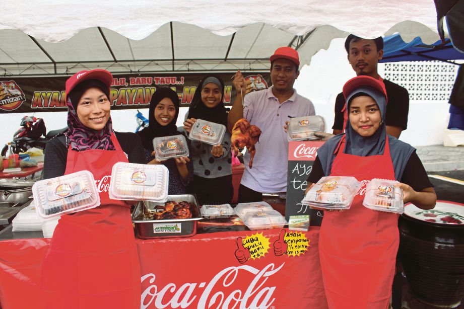 SYARIFUDDIN (tiga dari kanan) bersama pekerjanya menunjukan ayam panggang tempayan di jual di gerainya di Bazar Ramadan Kampung Melayu Majidee.