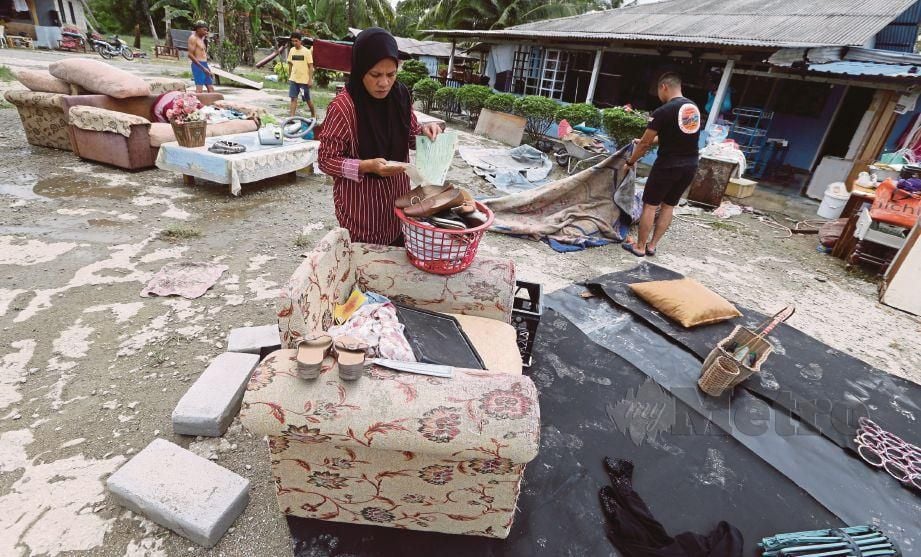 PENDUDUK Kampung Pulai bersama saudara-mara bergotong-royong membersihkan kawasan rumah yang terjejas akibat banjir.