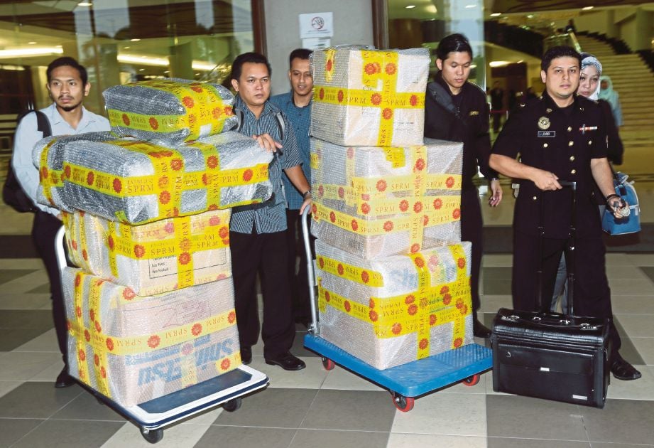   Pegawai dan anggota SPRM membawa barang yang disita  di Kompleks Mahkamah Jalan Duta, semalam.