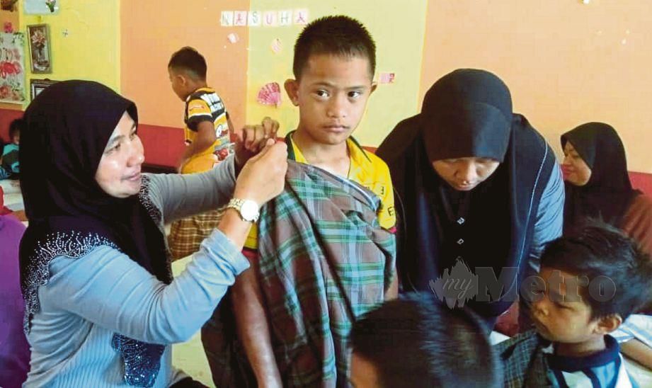 HABSAH  mengemaskan lilitan kain pelekat  Muhamad Haikal Haziq. FOTO Siti Rohana Idris